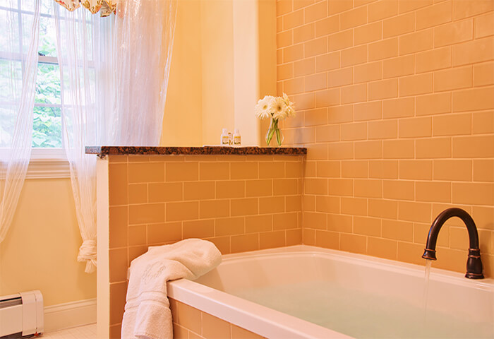 Pristinely clean bathroom features luxurious tub with bright white curtains