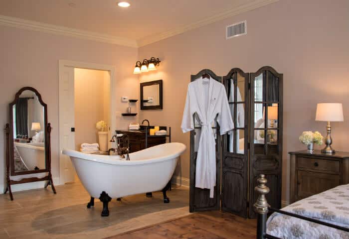 Cream walled en-suite featuring white clawfoot tub and mirrored privacy screen