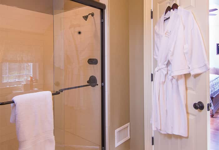 Shower in bathroom displays bright white towels, bathrobes and spa amenities