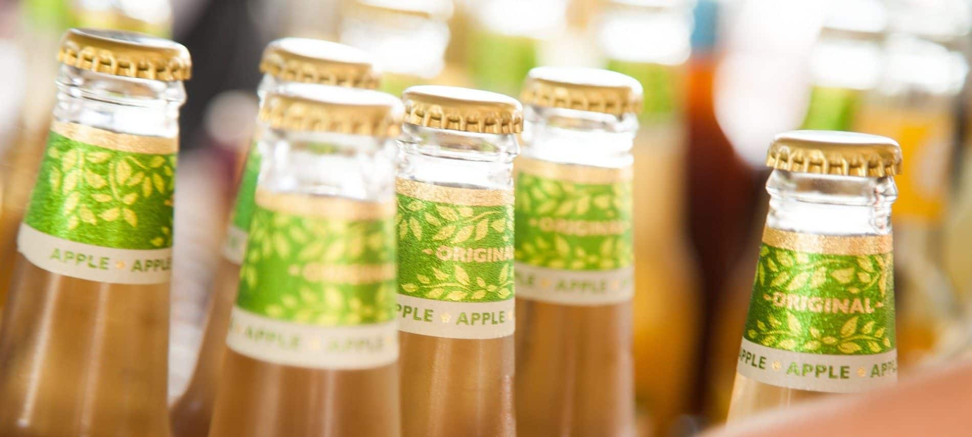 A grouping of several bottles of light apple cider with shiny green lables