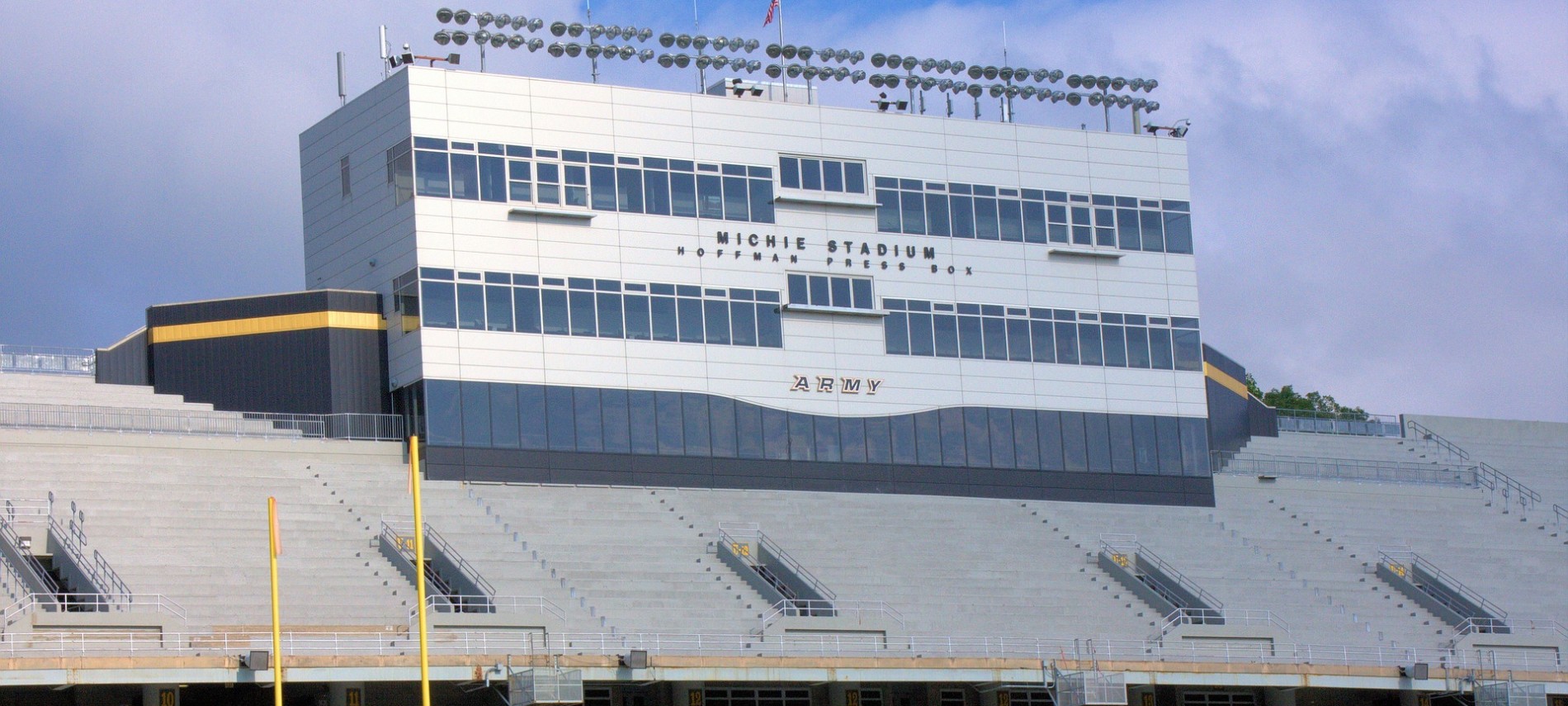 Expansive view of the outside of a large football stadium with blue sky in background