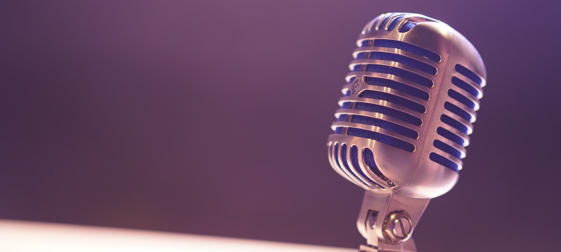 A single, silver vintage microphone against a dimly lit black background