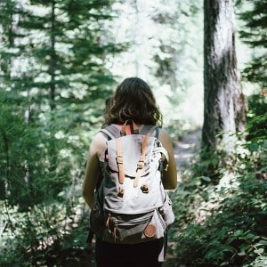 Woman in dense forest wearing a white and orange canvas backpack