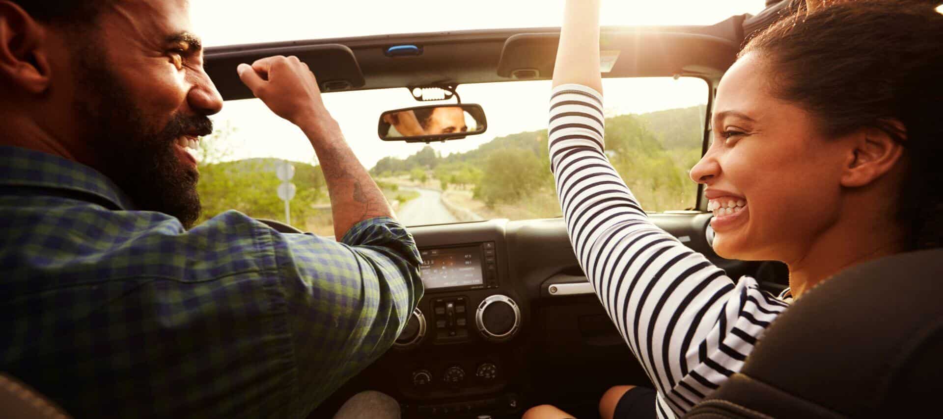 smiling couple in a convertible on a scenic drive during early autumn