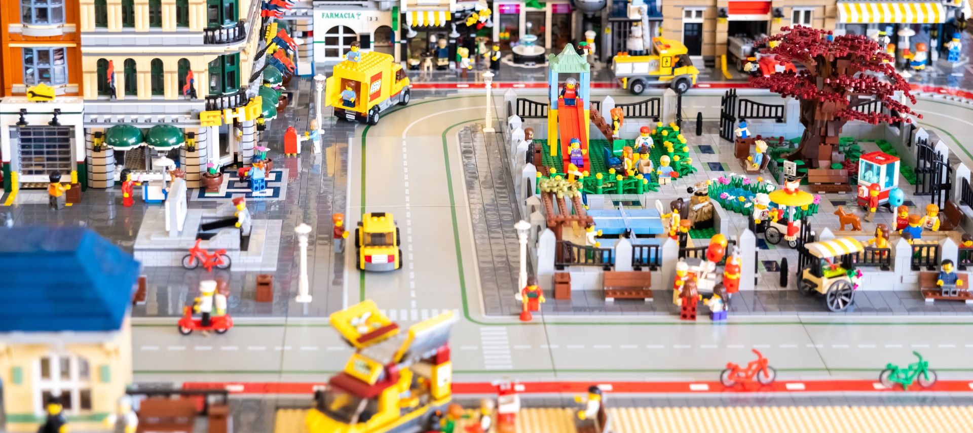 City block built entirely of legos with cars, park, and shops