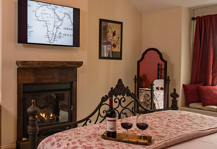 Floral quilt across a queen bed in a room with a fireplace, flat screen tv and comfortable sitting area.