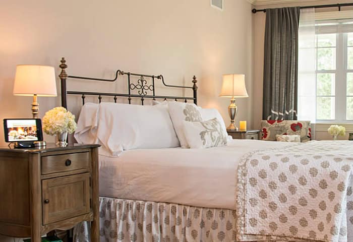 Crisp white linens on a queen bed with rought iron headboard and footboard