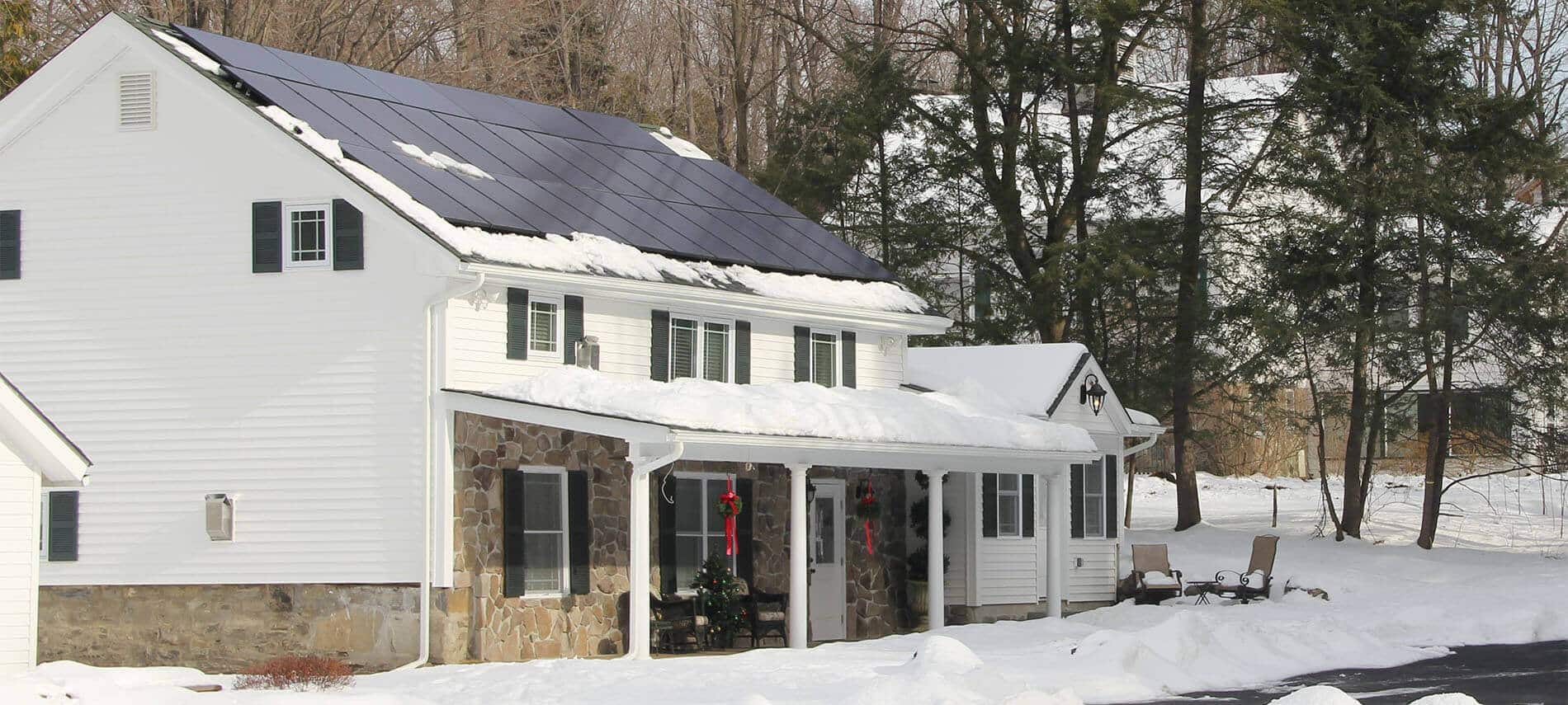 One story white home covered in snow with hollyberries on the doors.