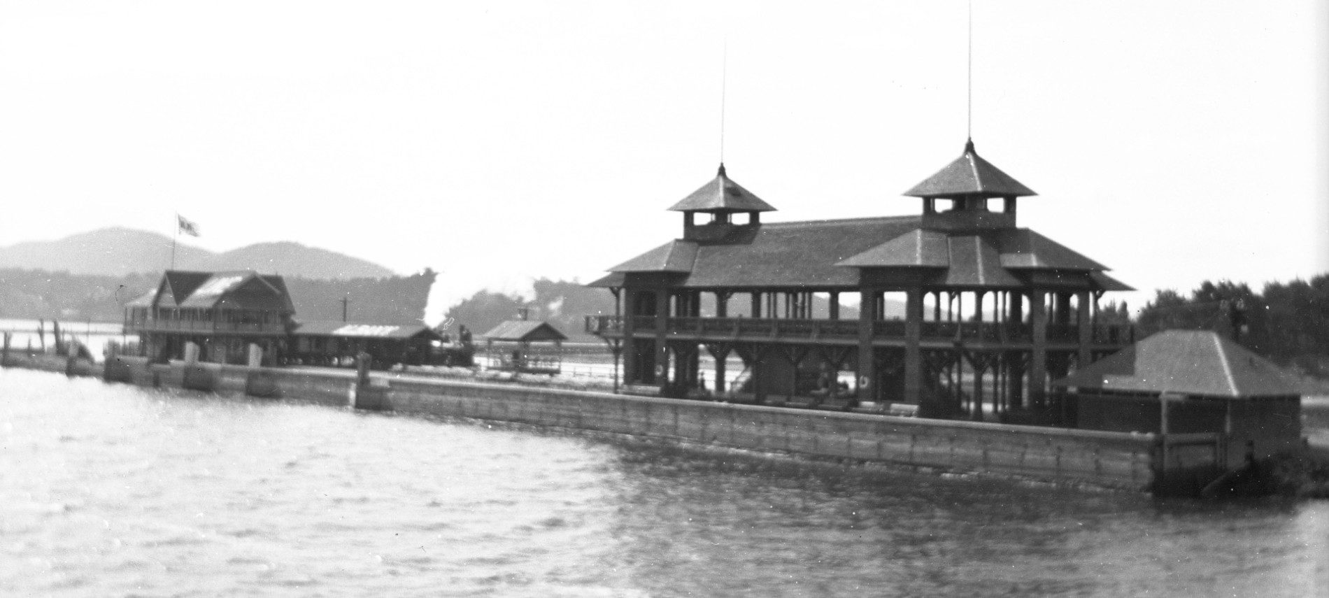 Black and white historic photo of two buildings on a point on a river