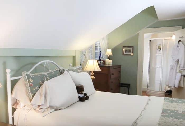 Soft green walls highlighting a white wrought iron queen bed