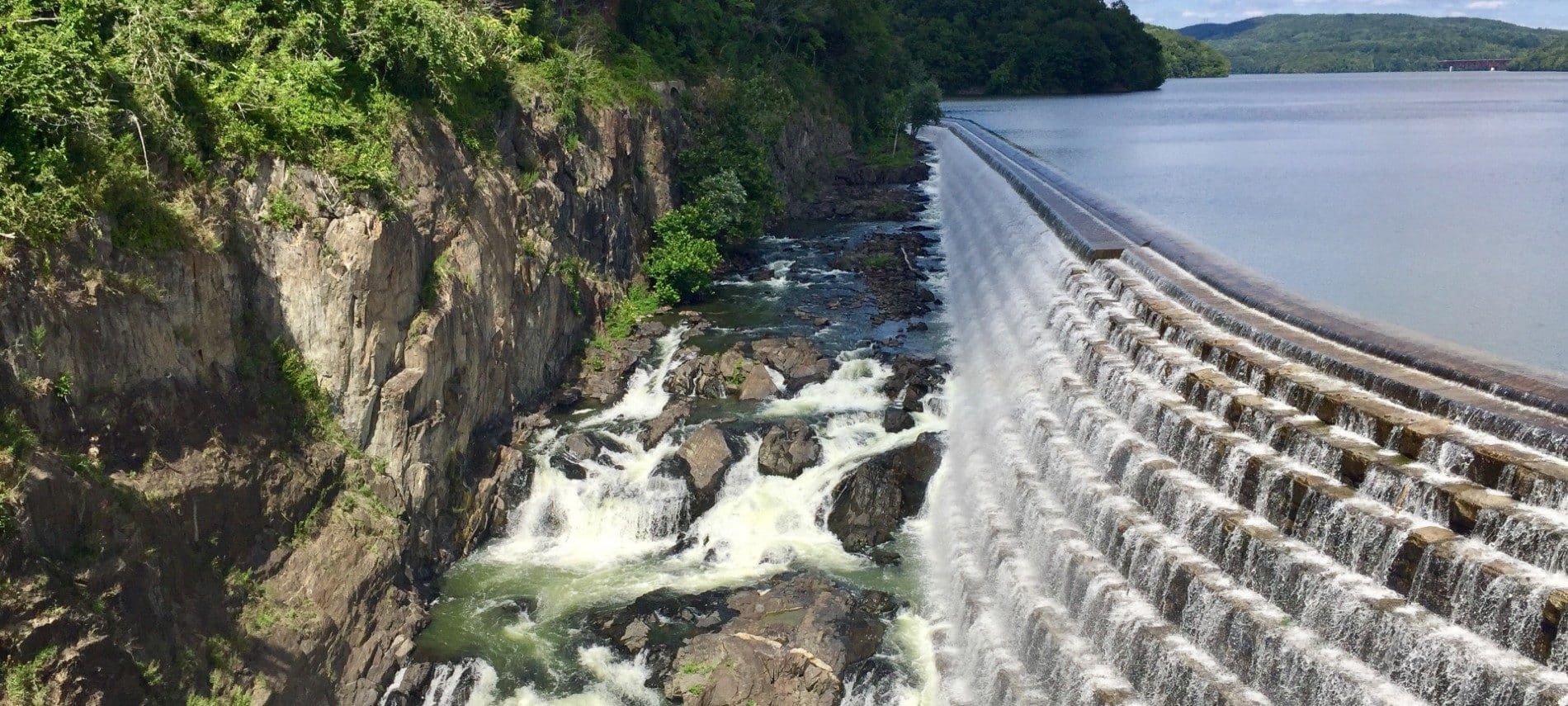 Expansive and unique retaining wall at a dam with water spilling over into a rocky gorge