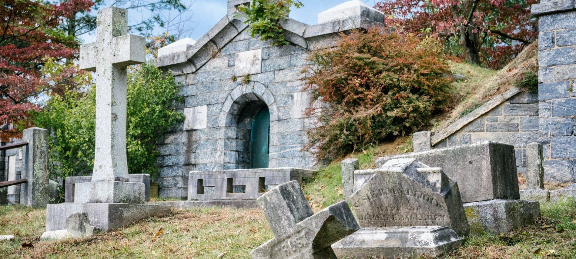 Cemetery with several large and small headstones and a large mausoleum