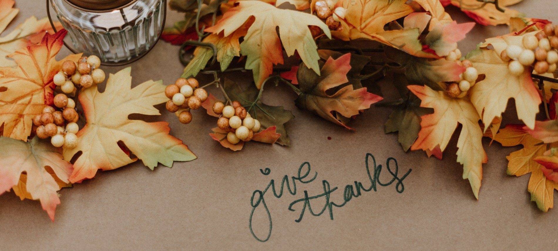 Brown, yellow and orange fall leaves on brown paper with written words give thanks