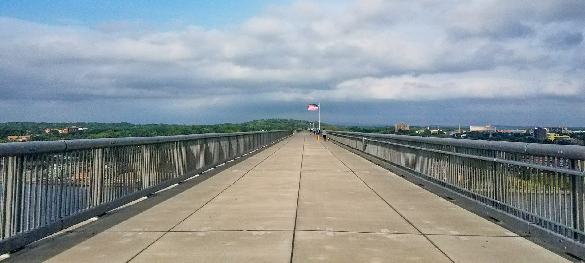 Large open walkway over a river with cloudy skies above