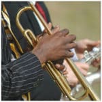 Two gentlemen playing instruments, one trumpet and one saxophone