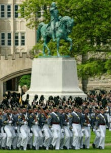 Group of military officers in front of a large statue of a horse at a military academy