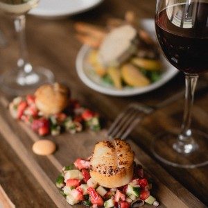 Two glasses of red wine on a wood table with small plate appetizers